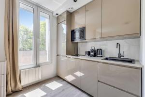a kitchen with white cabinets and a window at Cozy Studio 4P - Aubervilliers in Aubervilliers