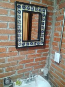 a mirror on a brick wall with a sink at Finca Itaca in San Esteban Tizatlán