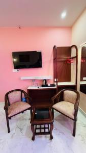 a room with two chairs and a desk and a tv at Hotel Singh Palace in Varanasi