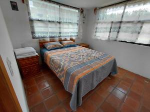 a small bedroom with a bed and two windows at Finca Itaca in San Esteban Tizatlán