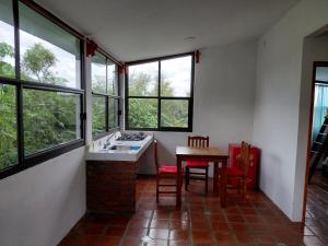 a kitchen with a table and chairs and windows at Finca Itaca in San Esteban Tizatlán