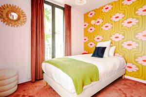 a bedroom with a bed and a flowery wallpaper at Le Charmant Hôtel in Saint-Ouen