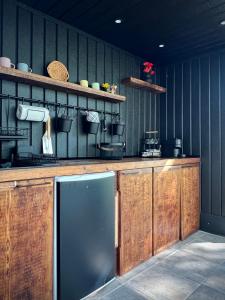 a kitchen with wooden cabinets and a black refrigerator at Bonair Tipi Village I Glamping in Călăţele