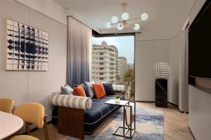 a living room with a couch and a large window at Canopy By Hilton Bangkok Sukhumvit in Bangkok