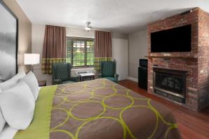 a hotel room with a bed and a fireplace at Super 8 by Wyndham Gananoque - Country Squire Resort in Gananoque