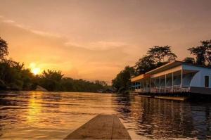 a house on a dock on a river at sunset at แพ ณ จันทร์ in Sathani Nam Tok