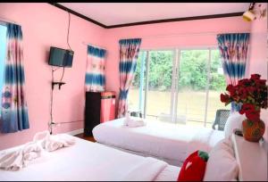 a pink bedroom with two beds and a window at แพ ณ จันทร์ in Sathani Nam Tok