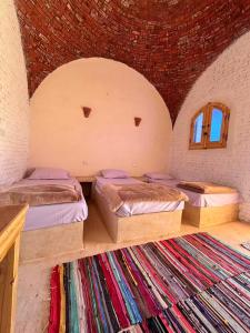 a bedroom with three beds in a room with a rug at Siwa Nostalgia Ecolodge in Siwa
