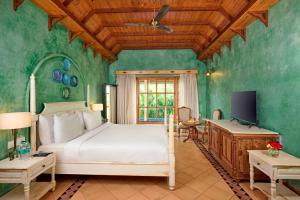 a bedroom with a white bed in a room with green walls at Golden Tulip Goa Mandrem in Mandrem