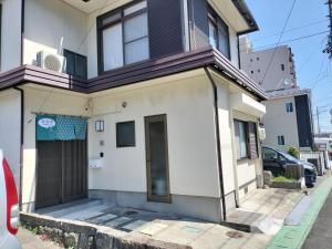 a white house with a garage on a street at 笑福邸 in Shiogama