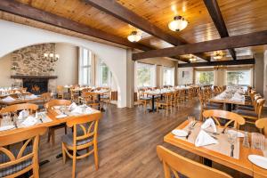 a restaurant with wooden tables and chairs and a fireplace at Hotel Cheribourg, an Ascend Collection Hotel in Magog-Orford