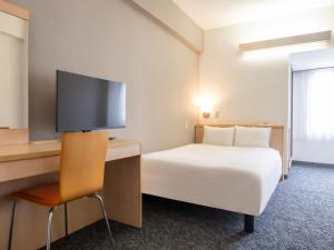 a hotel room with a bed and a desk with a tv at Chisun Inn Nagoya in Nagoya