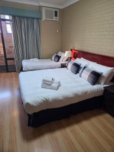 two beds in a hotel room with towels on them at Ashmont Inn Hotel in Wagga Wagga