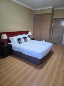 a bedroom with a large bed with white sheets at Ashmont Inn Hotel in Wagga Wagga