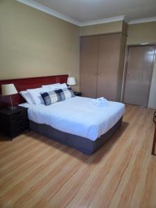 a bedroom with a large bed and a wooden floor at Ashmont Inn Hotel in Wagga Wagga