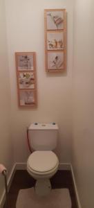 a bathroom with a toilet and two pictures on the wall at Aroma homes in Meru