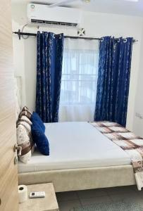 a bed in a room with blue curtains at Aroma homes in Meru