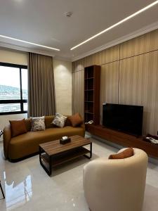 a living room with a couch and a tv at بيوت عطلات البيت الريفي للضيافه السياحي in Al Namas