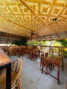 a restaurant with tables and chairs under a wooden roof at Pugad Hostel, El Nido in El Nido