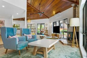 a living room with blue chairs and a white table at The Hidden Gem in Tamborine Mountain in Tamborine