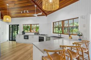 a kitchen with white counters and wooden ceilings and windows at The Hidden Gem in Tamborine Mountain in Tamborine