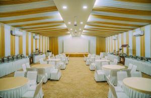 a room with white tables and white chairs in a room at Raphilhin The Business Hotel in Perintalmanna +29 photos