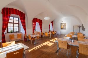 a restaurant with tables and chairs and red curtains at Hotel Adalbert in Prague