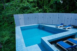 a swimming pool with two blue chairs and a fence at Raphilhin The Business Hotel in Perintalmanna