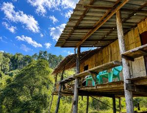 a wooden house with a thatched roof at Teepo Ke Hillside Jungle Lodge in Ban Mae Sapok Nua