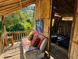 a couch sitting on the back of a porch at Teepo Ke Hillside Jungle Lodge in Ban Mae Sapok Nua