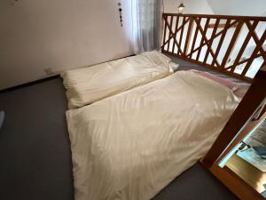 a bed with white sheets in a room at Azumi Holiday House in Azumino