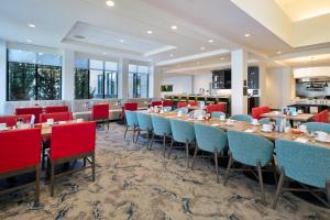 a dining room with tables and chairs and windows at Hilton Garden Inn Akron in Akron