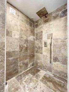 a bathroom with a shower with tiled walls at Spacious house 300m from the beach in Hermanville-sur-Mer