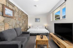 a living room with a couch and a tv at Rock On Studio in Jindabyne