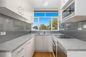 a kitchen with white cabinets and a large window at Rock On Studio in Jindabyne