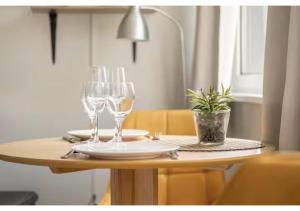 a table with two wine glasses and a potted plant at L'Essentiel Confort moderne - équipements premium et tram à 5 minutes in Strasbourg