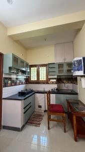 a large kitchen with white cabinets and a red chair at Gravity Groups Core - Sakthi residency in Puducherry Airpoert