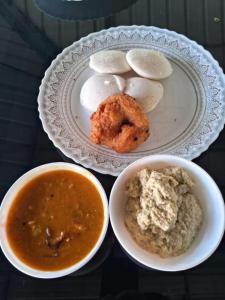 a table with a plate of food and a bowl of soup at Tara inn in Alwaye