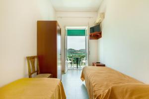 two beds in a room with a balcony at Hotel Riviera in Procida