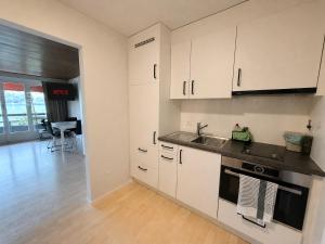 a kitchen with white cabinets and a sink at Sunshine Suite in Ingenbohl