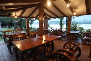 a restaurant with wooden tables and chairs on a deck at Thimura Resort in Bharatpur