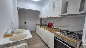 a kitchen with white cabinets and a stove top oven at Unirii Residence in Bacău +7 photos