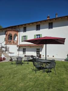 a table and chairs with an umbrella in front of a building at Bed and Breakfast Cascina Morelli 1862 in Avigliana