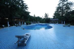 a swimming pool with a table and benches in it at Thimura Resort in Bharatpur