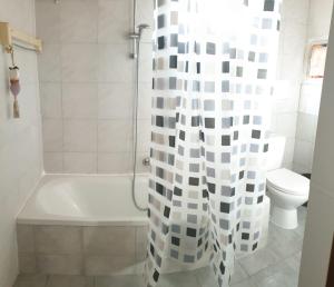 a bathroom with a tub and a toilet and a shower curtain at 487 Rue des Grappins in Bouhans +9 photos