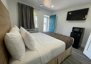 a bedroom with a bed with a tv on the wall at Sun Valley Motel in Phoenix