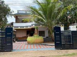 a house with a palm tree in front of a gate at Soul Shore, Varkala in Varkala