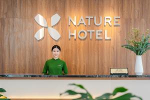 a woman standing in front of a nirvana hotel at Nature Hotel - Le Hong Phong in Da Lat