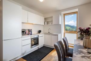 a kitchen with white cabinets and a table with chairs at Martinshof in Sankt Johann in Tirol