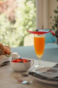 a glass of orange juice next to a bowl of fruit at B&B Maaltebrug in Ghent